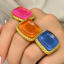 Pink orange and blue chunky resin rings styled together on hand