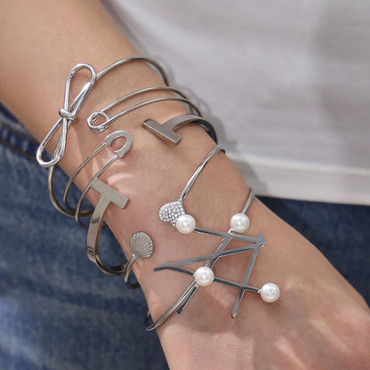 Model stacking polished silver geometric line & pearl open bangles, trendy minimalist accessory