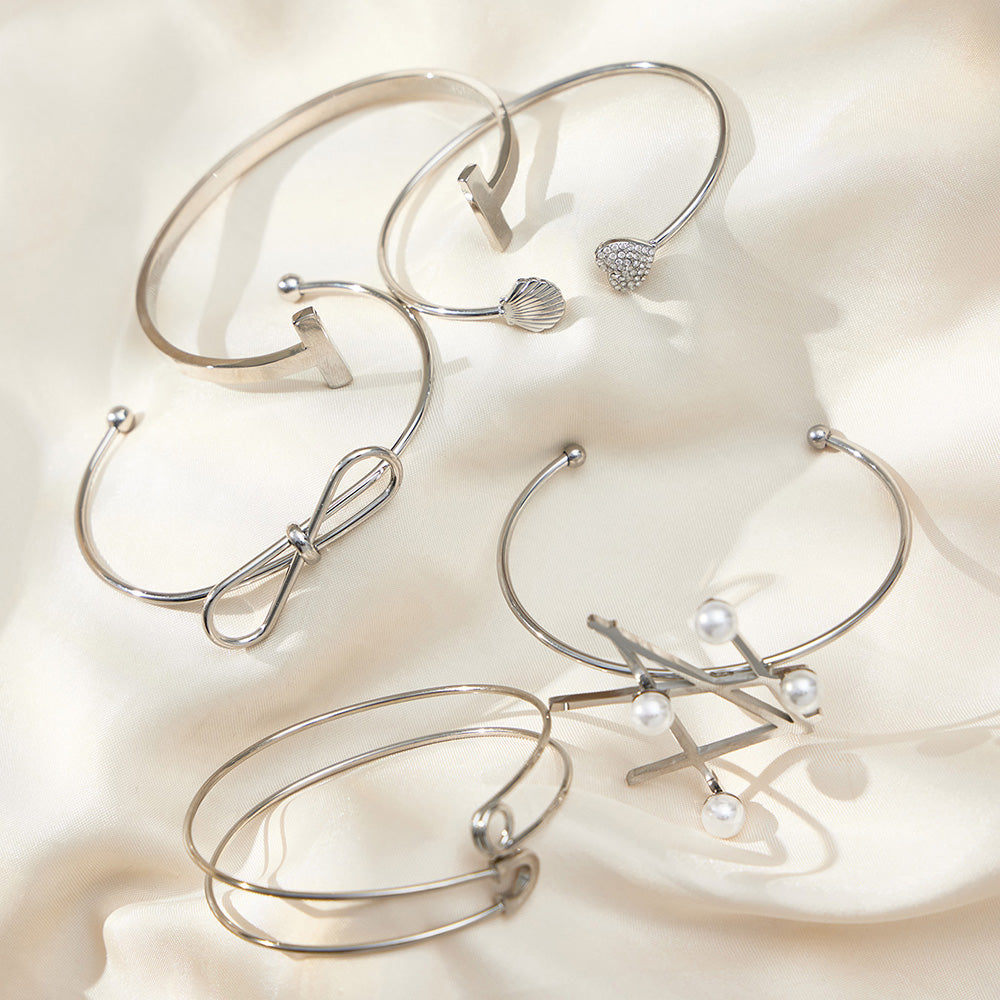 Polished silver geometric line & pearl open bangle set displayed on silk, minimalist INS jewelry