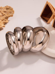 polished silver stainless steel wide cuff bracelets displayed with natural stone and sunglasses, modern minimalist scene