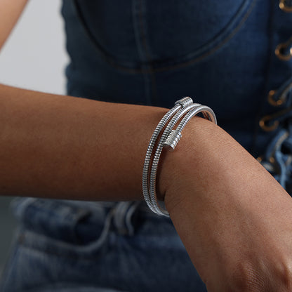 model wearing polished silver titanium steel snake bone chain bracelet, stacked style, casual denim outfit accessory