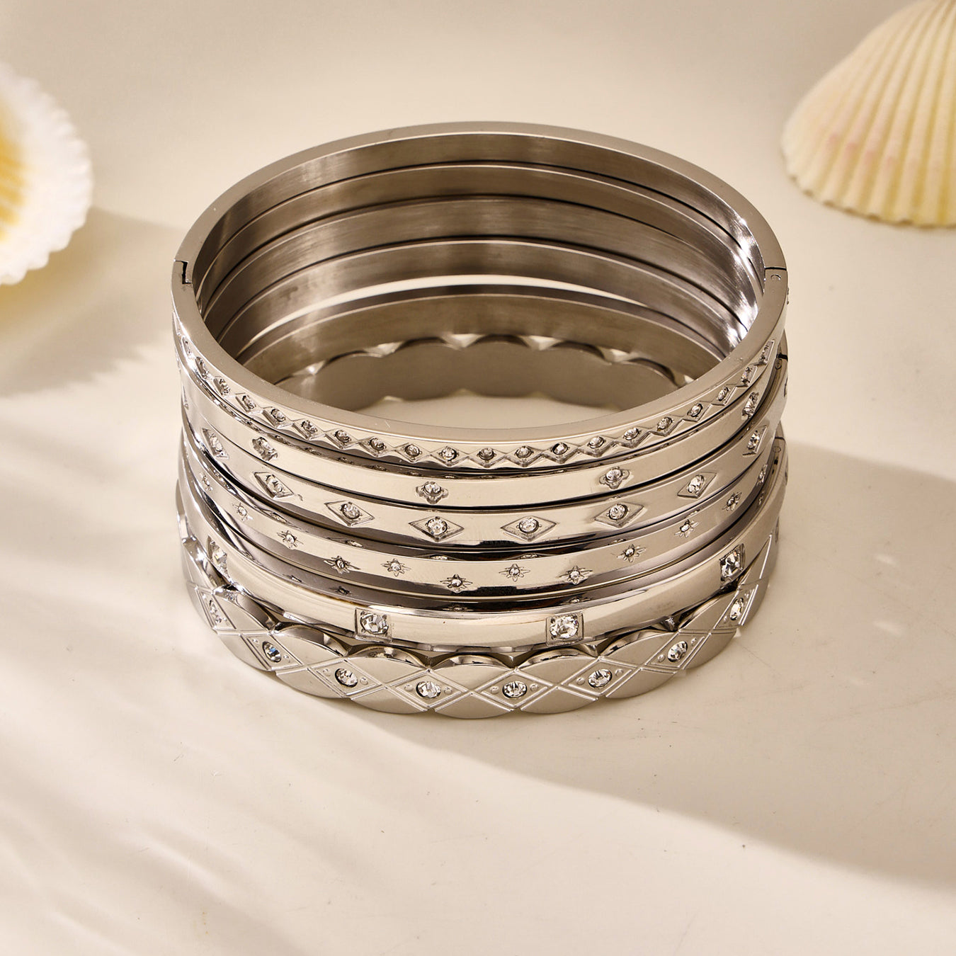 polished silver titanium steel zircon bangle set displayed with seashells, sleek minimalist jewelry