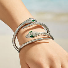 Model wearing stacked polished steel snake open bangles with green zircon eyes