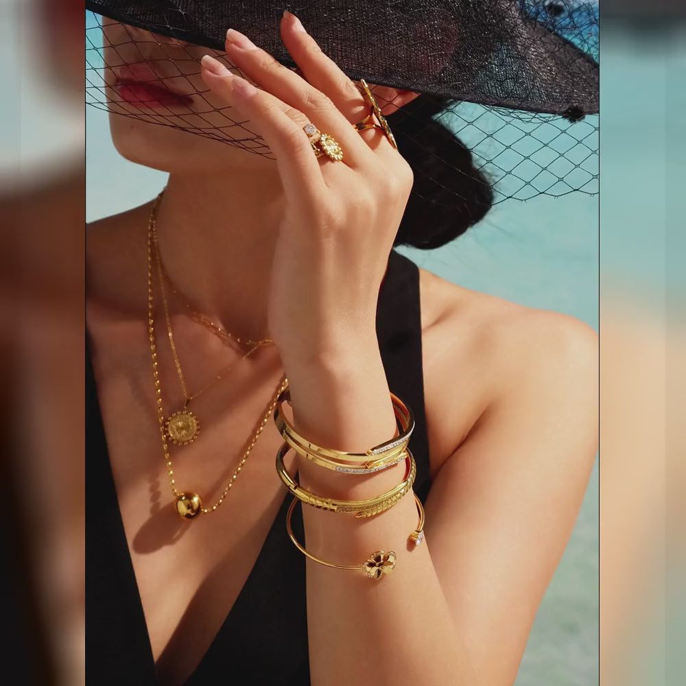 Video showing gold-tone and steel-tone nail bangle bracelets with pink and clear zircon accents in close-up and layered wrist styling views