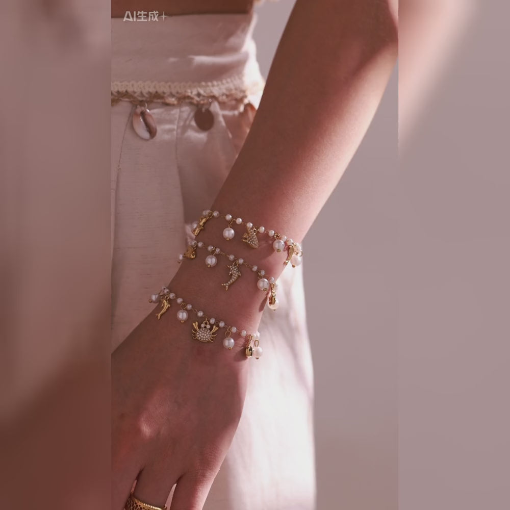 Gold-tone pearl charm bracelets with dolphin, starfish and crab details worn by a model