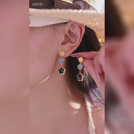 Gold-tone floral charm earrings and bracelets with colorful accents shown on a model