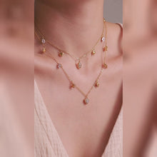 Layered gold-tone necklaces with dangling heart charms and clear stone pendants, shown on a model.