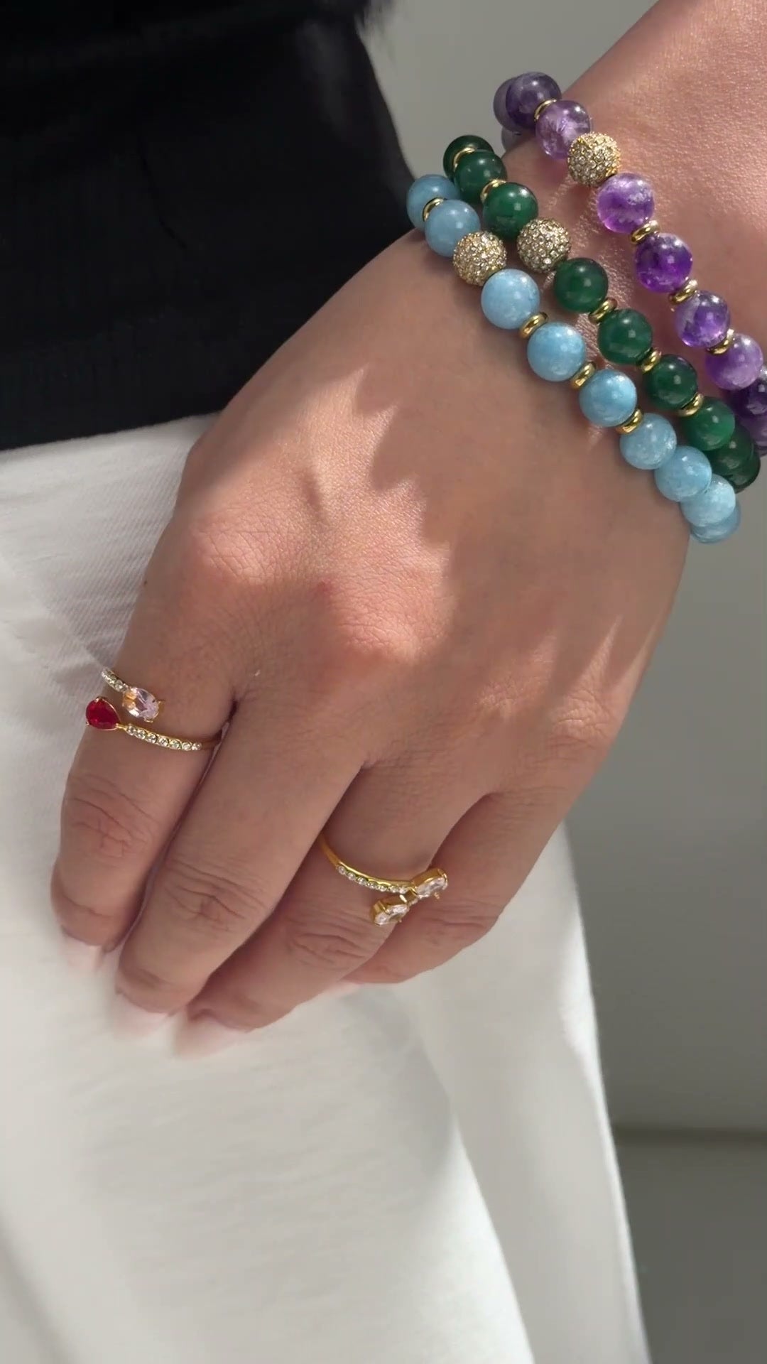 Colorful round-bead bracelets with gold-tone spacers and sparkling accent beads shown stacked on the wrist.