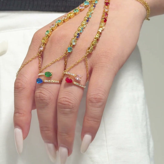 Gold-tone hand chains with multicolored stones draped from the wrist to the fingers.