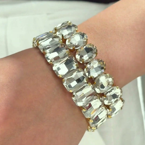 Statement bracelets with large clear rectangular and round stones, shown stacked on a model's wrist.