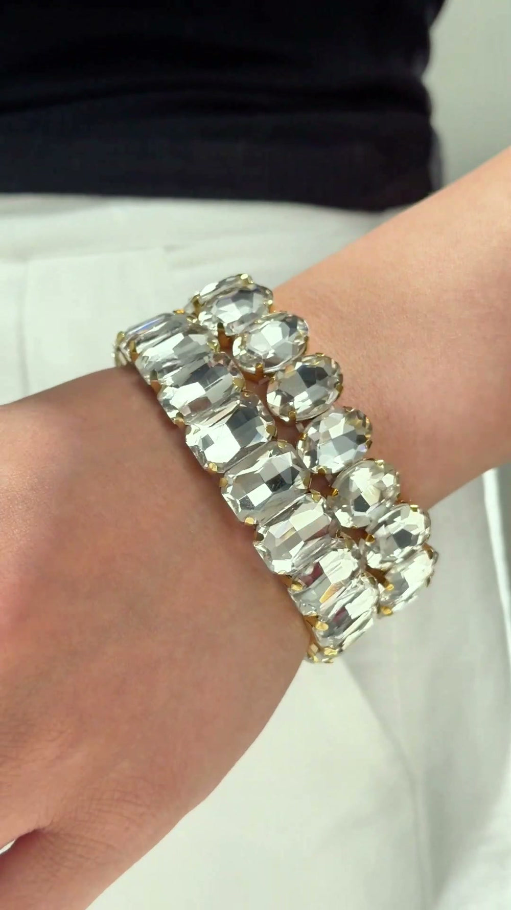 Statement bracelets with large clear rectangular and round stones, shown stacked on a model's wrist.