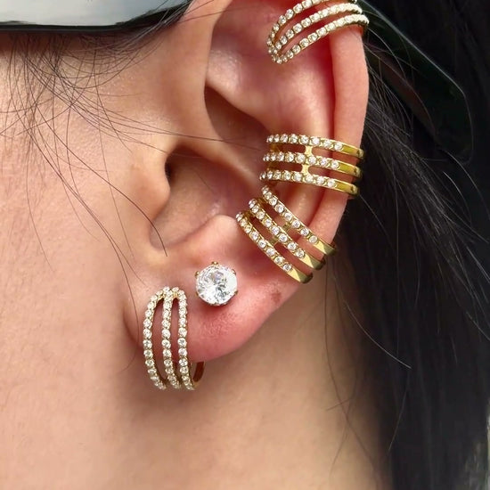 Gold-tone triple-row ear cuffs and hoop earrings with clear stone accents, shown on a model.