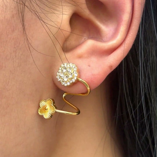 Gold-tone spiral earrings with textured flowers and clear stone clusters, shown on a model.