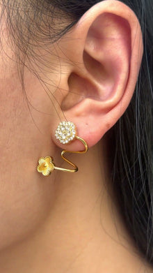 Gold-tone spiral earrings with textured flowers and clear stone clusters, shown on a model.