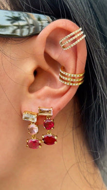 Gold-tone drop earrings with rectangular, round and oval pink and red stones, shown on a model.