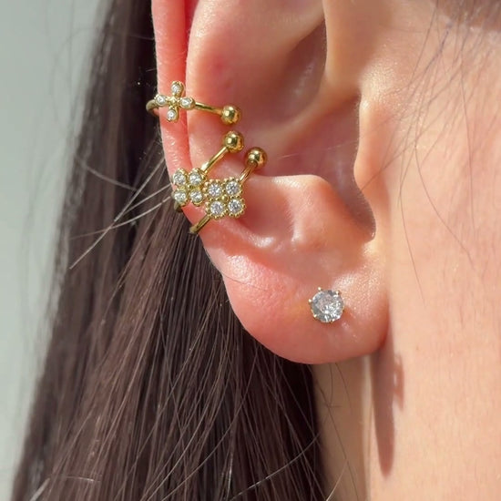 Gold-tone ear cuffs with delicate floral details and clear sparkling stones shown on the ear.