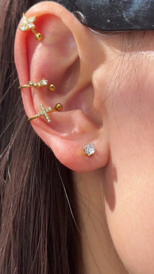 Slim gold-tone ear cuffs with clear stone accents and polished ball ends styled along the ear.