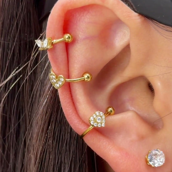 Gold-tone ear cuffs with clear heart-shaped and geometric stone details shown stacked on the ear.