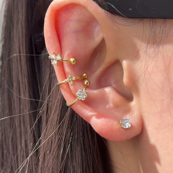  Delicate gold-tone ear cuffs with clear sparkling floral accents styled along the ear.