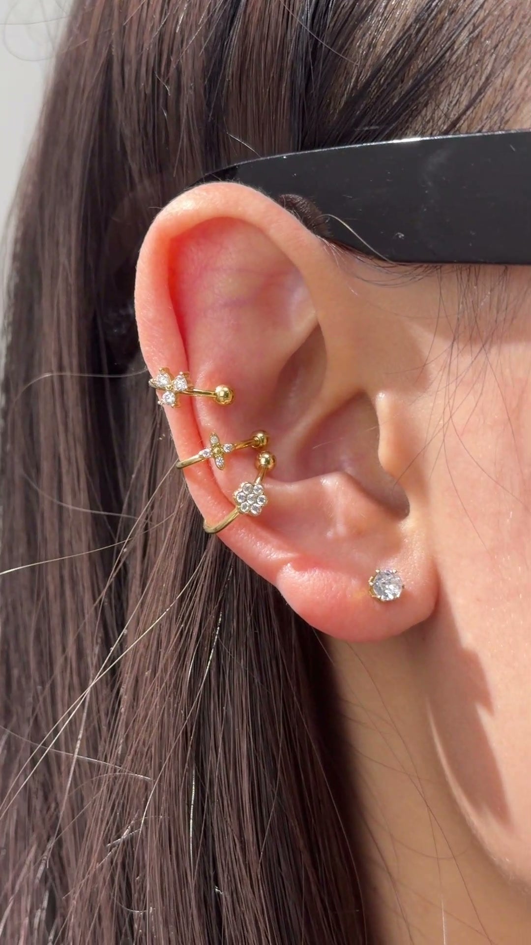  Delicate gold-tone ear cuffs with clear sparkling floral accents styled along the ear.