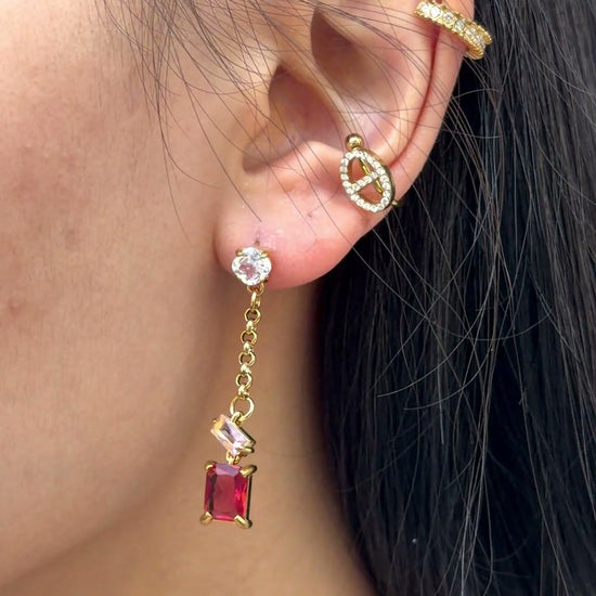 Video showing red zircon drop earrings worn on the ear with geometric linked details and gold PVD finish
