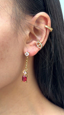 Video showing red zircon drop earrings worn on the ear with geometric linked details and gold PVD finish