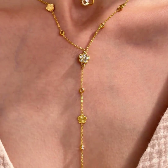 Layered gold-tone necklaces featuring a butterfly pendant and a floral Y-shaped lariat with clear stone accents, shown on a model.
