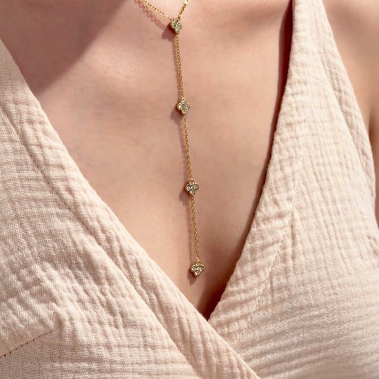 Gold-tone Y-shaped lariat necklace with clear-stone four-petal floral stations, shown on a model.