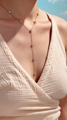 Gold-tone Y-shaped lariat necklace with clear-stone four-petal floral stations, shown on a model.