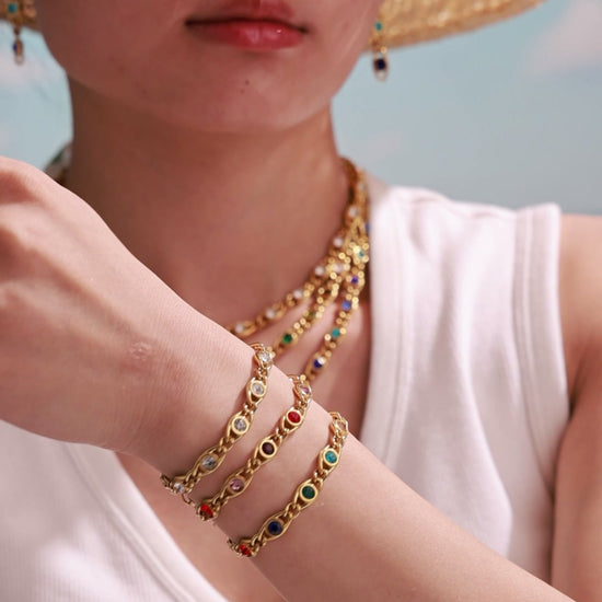 Model wearing gold-tone chain bracelets with clear and multicolor round stones in bezel settings.