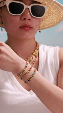 Model wearing gold-tone chain bracelets with clear and multicolor round stones in bezel settings.