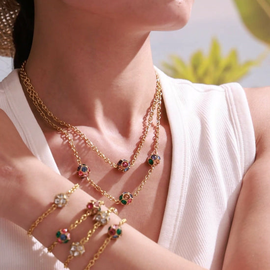 Model wearing gold-tone chain bracelets with clear and multicolor round stones in bezel settings.
