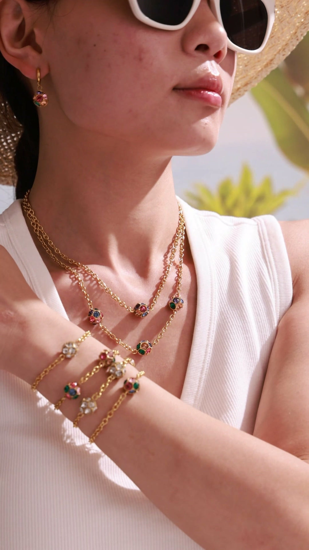 Model wearing gold-tone chain bracelets with clear and multicolor round stones in bezel settings.
