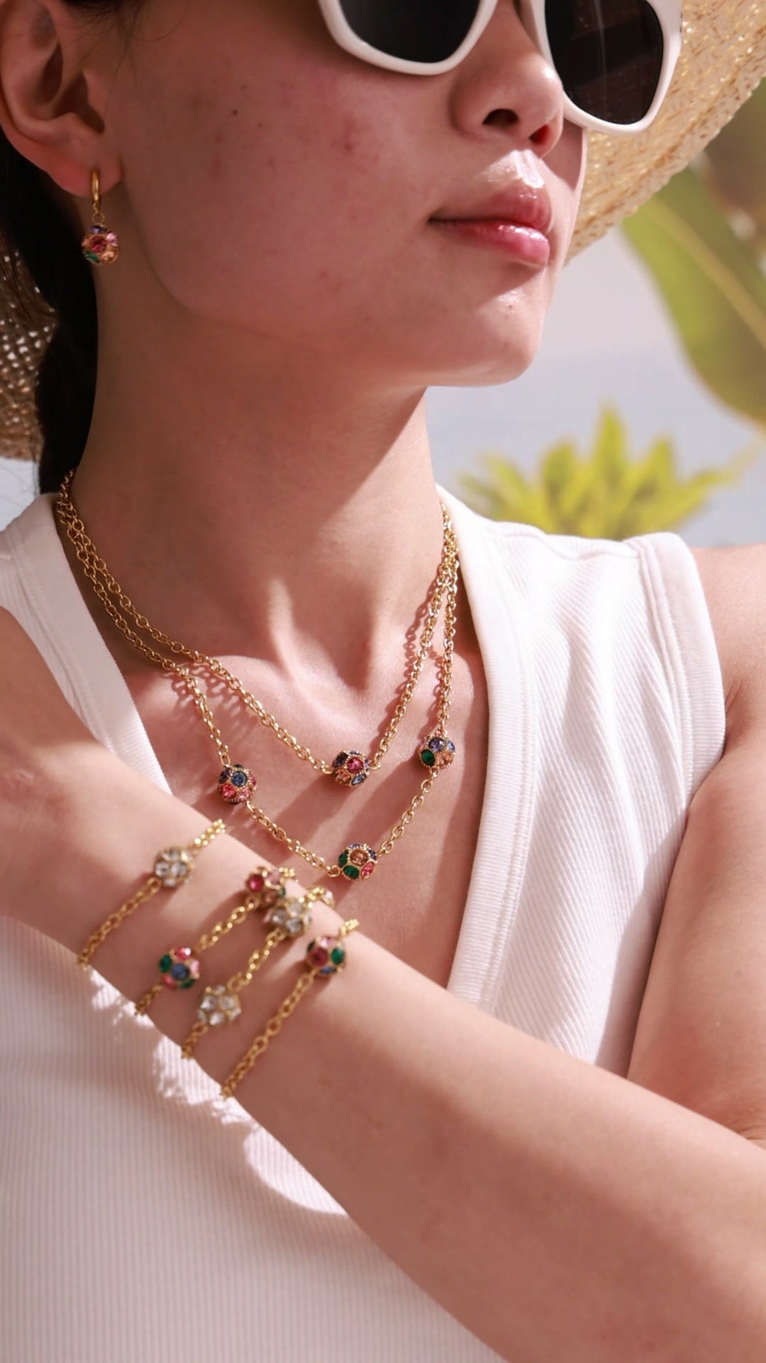 Model wearing gold-tone chain bracelets with clear and multicolor round stones in bezel settings.