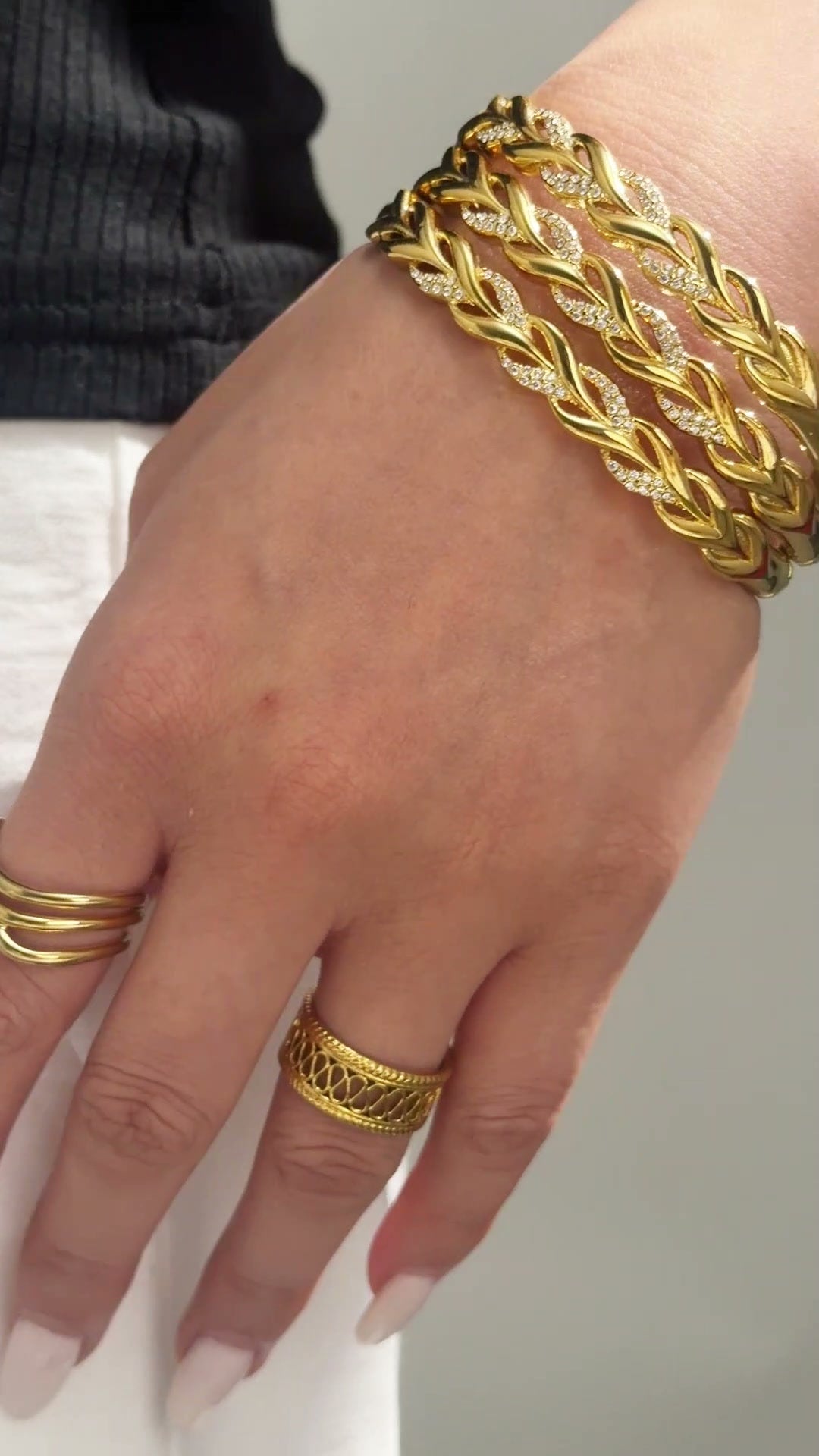 Wide gold-tone openwork cuff bracelet with interwoven leaf-shaped links shown on the wrist.