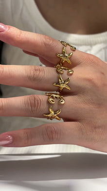 Gold-tone ocean-inspired open rings with zircon starfish and crab details, shown on hand