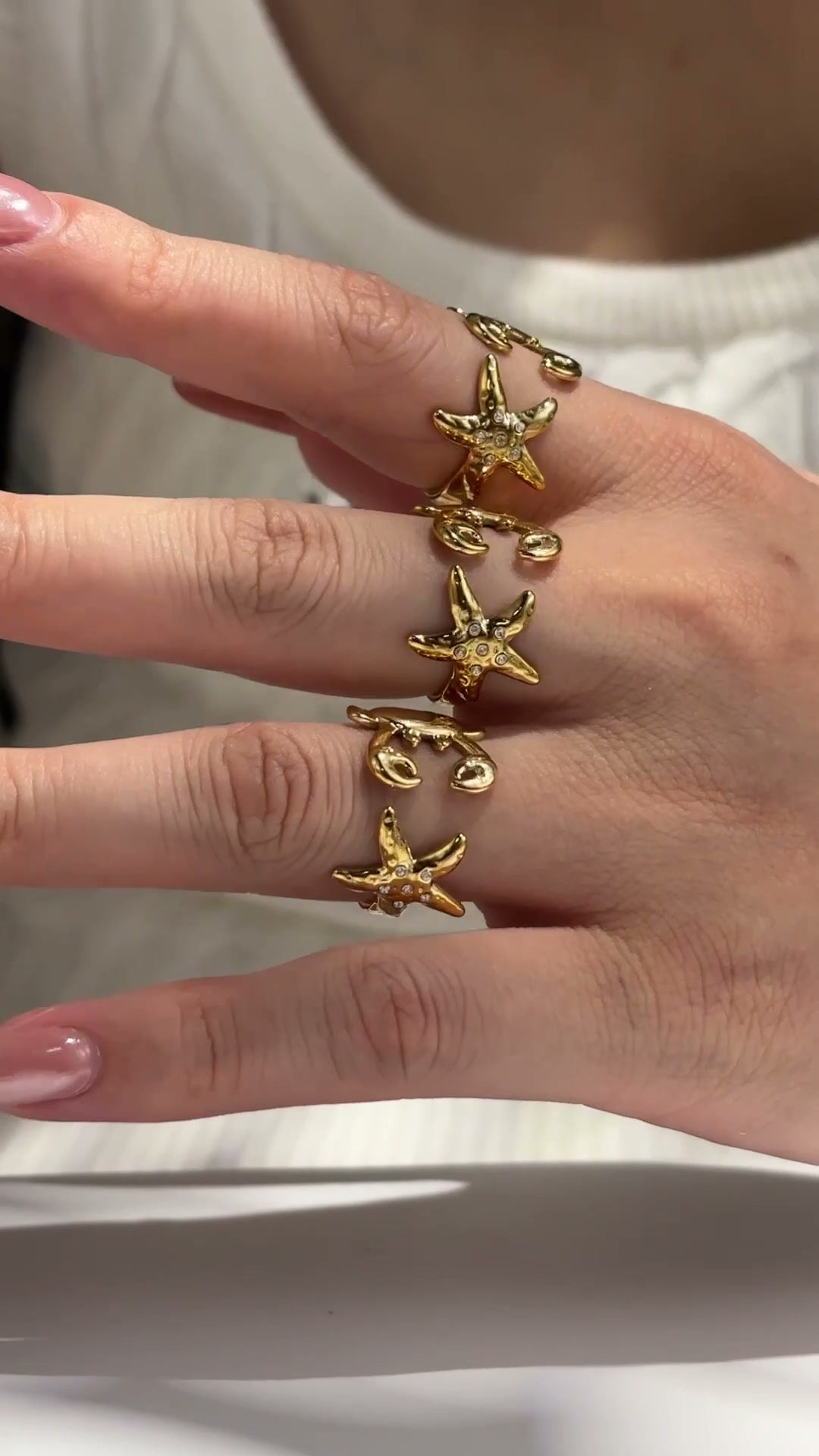 Gold-tone ocean-inspired open rings with zircon starfish and crab details, shown on hand