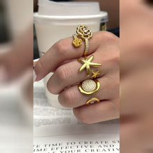 Video of A442 flower, A443 pavé disc and A444 starfish gold-tone stainless steel rings styled together on a model's hand. Each ring is sold separately.