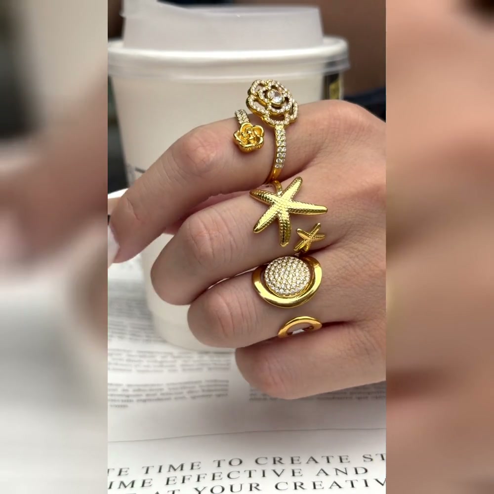 Video of A442 flower, A443 pavé disc and A444 starfish gold-tone stainless steel rings styled together on a model's hand. Each ring is sold separately.