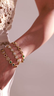 Gold-tone heart-link bracelets with clear and multicolor crystal accents worn by a model