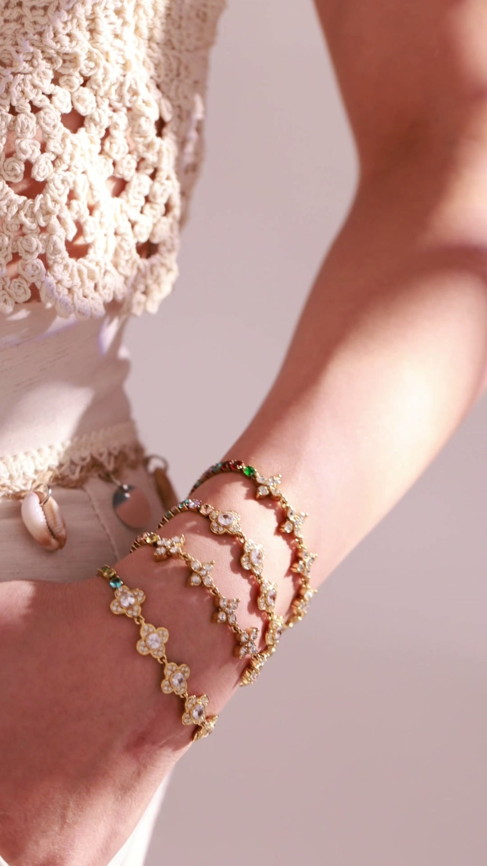 Gold-tone floral bracelets with clear crystal details and colorful accents worn by a model