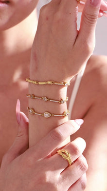Delicate gold-tone bracelets with clear crystal eye and teardrop accents worn by a model