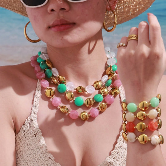 Video of a model styling a colorful resin necklace and bracelet jewelry set with layered summer fashion looks.