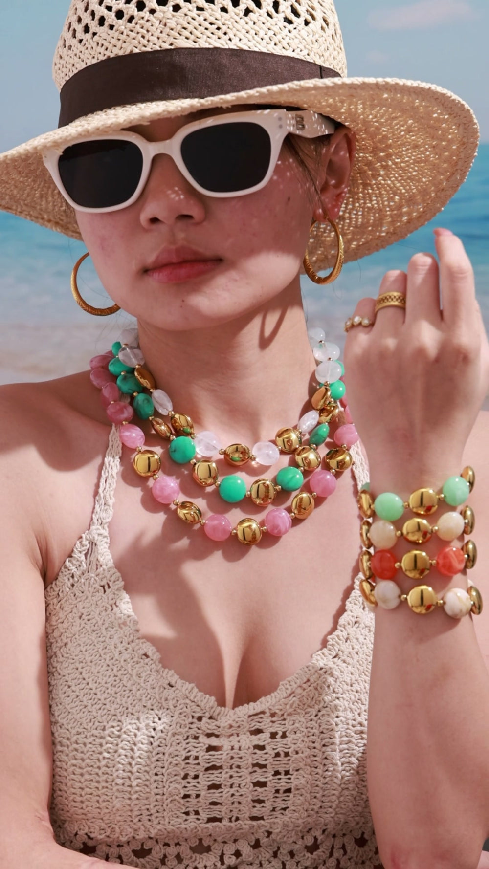 Video of a model styling a colorful resin necklace and bracelet jewelry set with layered summer fashion looks.