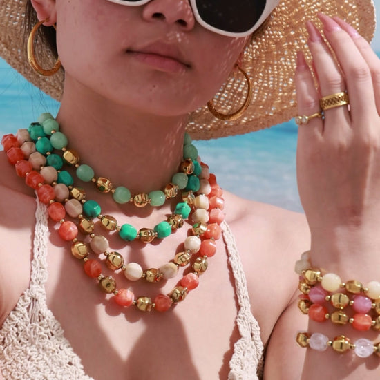 Video of a model wearing layered colorful resin bead necklaces and stacked matching bracelets with a bold resort-inspired styling look.