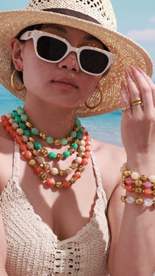 Video of a model wearing layered colorful resin bead necklaces and stacked matching bracelets with a bold resort-inspired styling look.