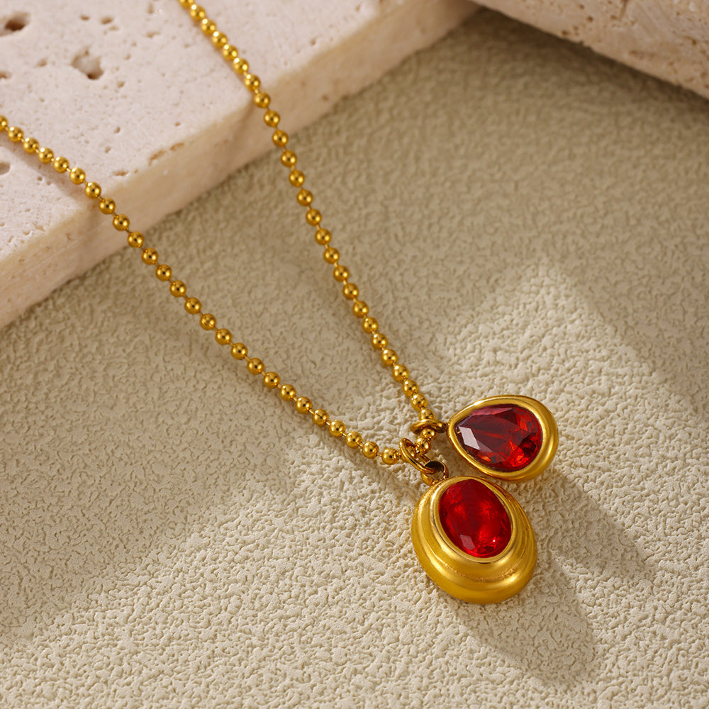 Close-up of a red oval zircon necklace with a clear teardrop accent pendant