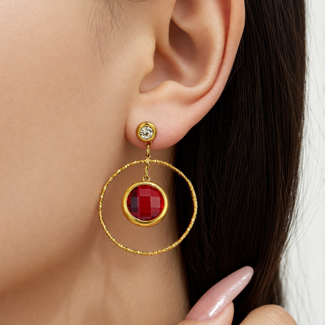 Model wearing red glass stone drop earrings in a gold-tone circular design