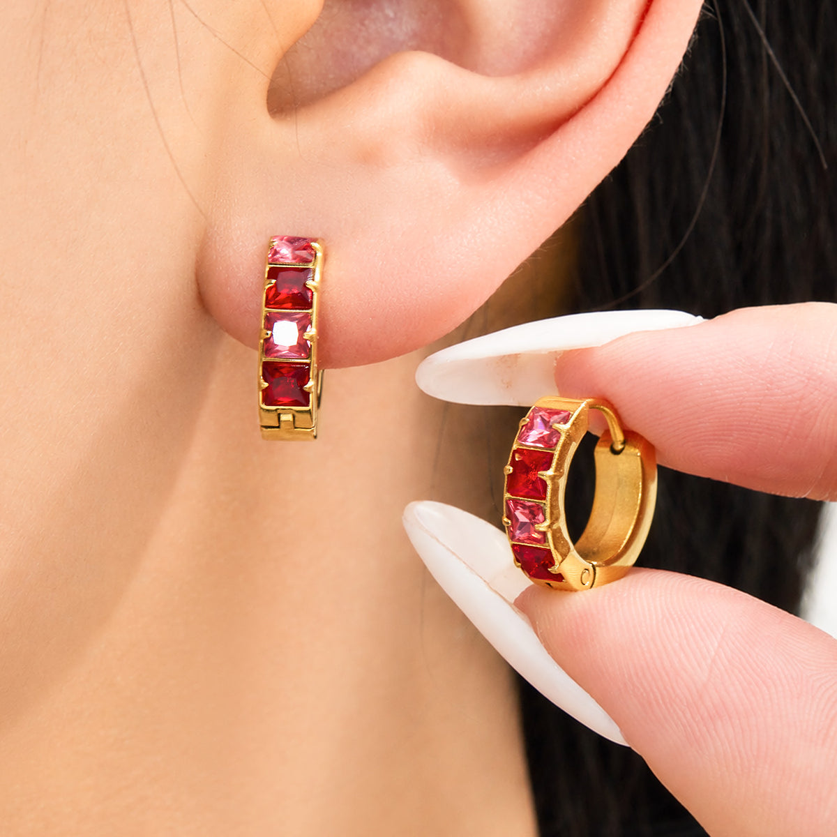 Stainless steel huggie earrings with red and multicolor cubic zirconia worn on ear