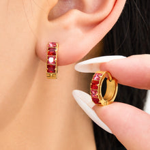 Stainless steel huggie earrings with red and multicolor cubic zirconia worn on ear